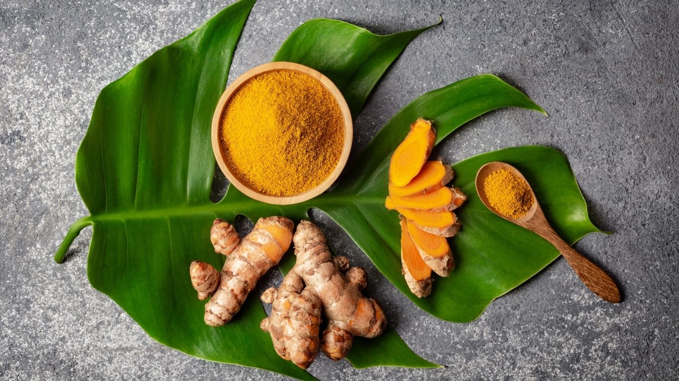 “Cúrcuma natural en polvo y raíz fresca sobre fondo claro representando cómo tomar cúrcuma según el objetivo de salud